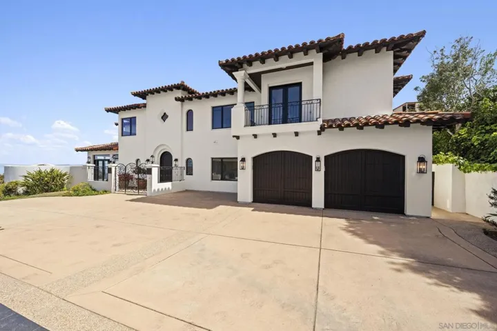 Mediterranean-style residence with a grand motor court and dual arched garages, where classic architecture and warm coastal tones create a stately arrival in a private La Jolla hillside setting.