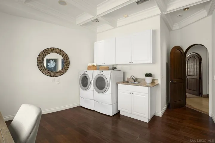 Large laundry room with space for multiple desks and a custom coffered ceiling, blending functionality with thoughtful design for everyday organization and workspace flexibility.