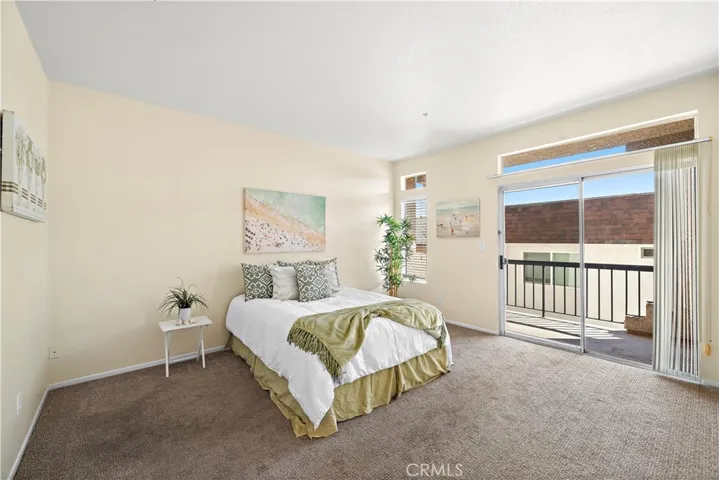 Spacious primary bedroom. 2 of two bedrooms with carpet and a balcony.