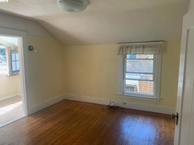 Bonus room with dark wood-type flooring and baseboards