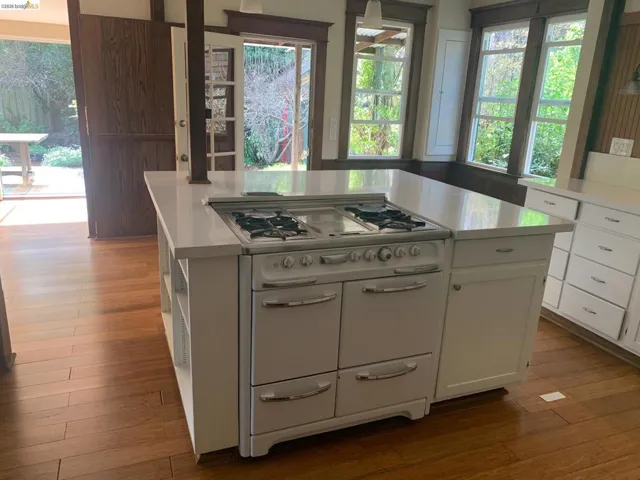Kitchen featuring a kitchen island, double oven range, light countertops, white cabinetry, and dark wood finished floors