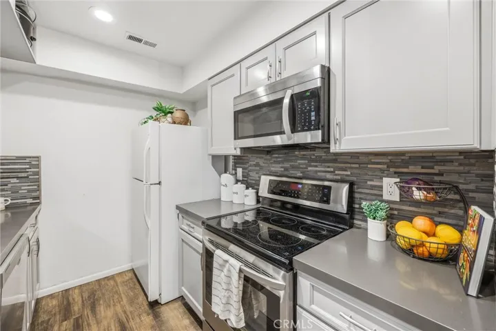 Kitchen features new cabinets, backsplash, wood laminate flooring