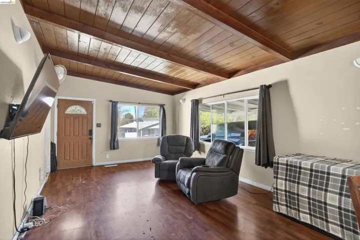 Sitting room with wood ceiling, dark wood-style floors, and vaulted ceiling with beams