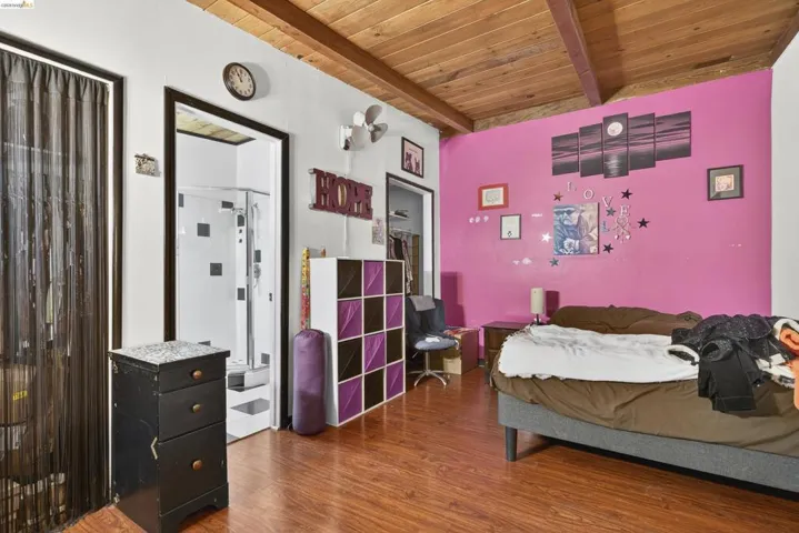 Bedroom with a wooden ceiling with exposed beams and wood finished floors