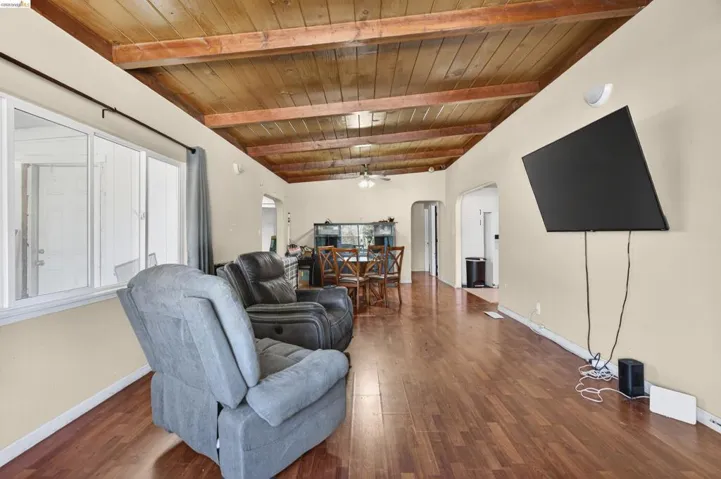 Living area featuring arched walkways, a wood ceiling with exposed beams, wood finished floors, and a ceiling fan