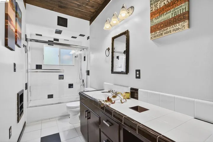 Full bathroom featuring vanity, bath / shower combo with glass door, light tile patterned floors, and wood ceiling