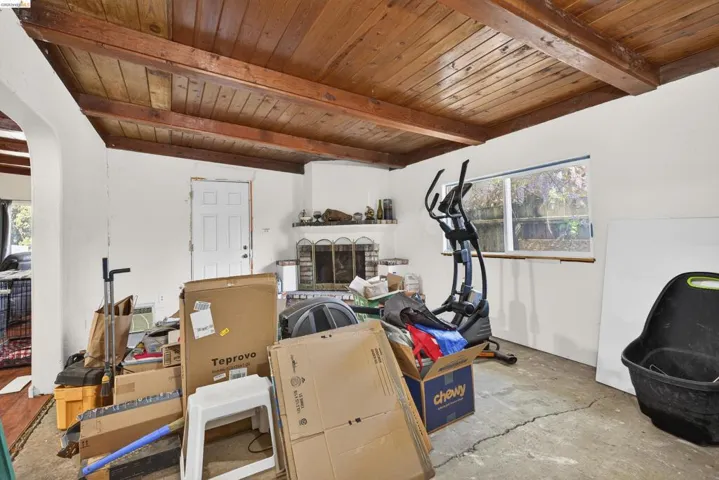 Exercise area with a wooden ceiling with exposed beams, concrete floors, and a fireplace