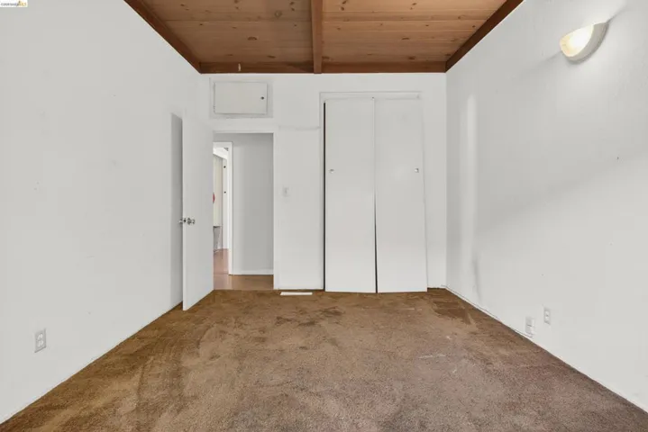 Unfurnished bedroom featuring wood ceiling, carpet flooring, and a closet