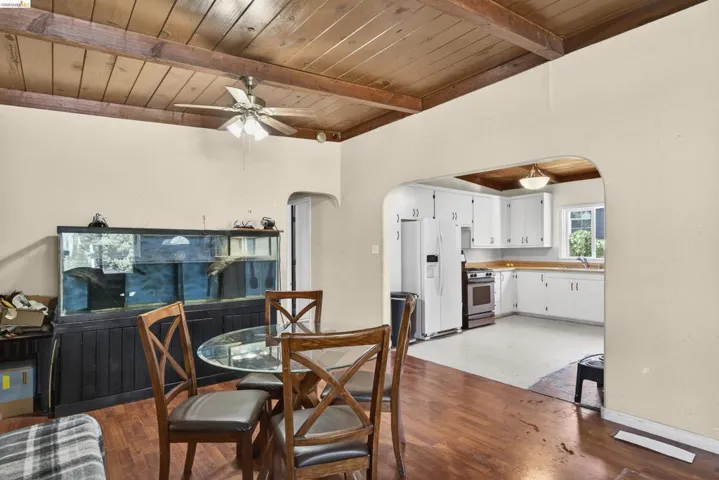 Dining room with a wooden ceiling with exposed beams, arched walkways, a ceiling fan, and wood finished floors