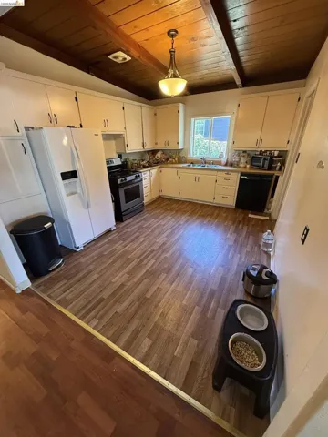 Kitchen featuring wood-finish flooring, white cabinetry, and exposed wood beam ceiling