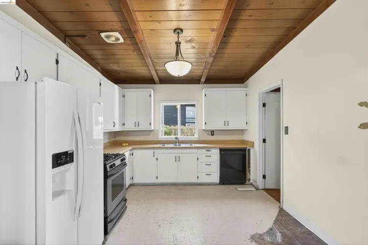 Kitchen with white refrigerator with ice dispenser, light countertops, hanging light fixtures, dishwasher, and range with gas stovetop