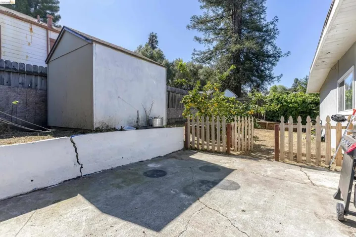 Fenced backyard with a patio area, an outbuilding, and area for grilling