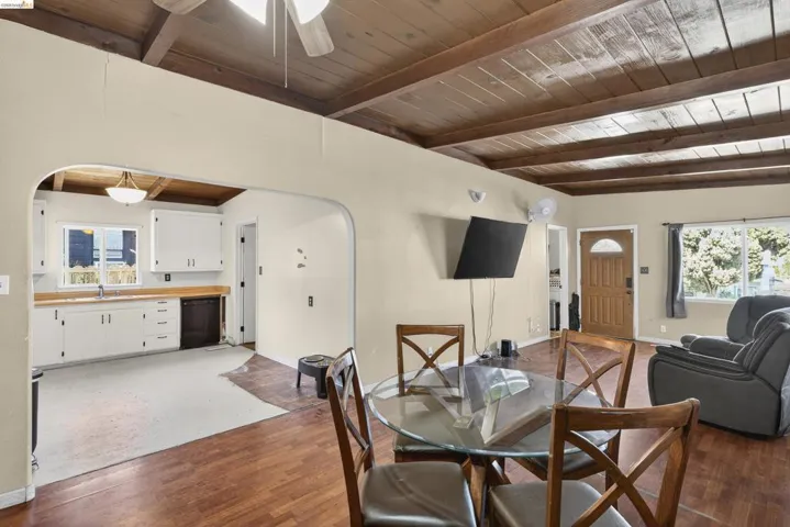 Dining space featuring arched walkways, plenty of natural light, a wood ceiling with exposed beams, and dark wood-style flooring