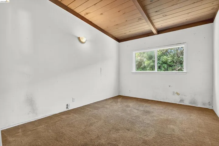 Spare room featuring carpet flooring and a vaulted wood ceiling