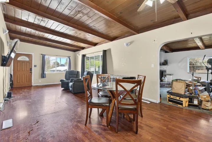 Dining space with a wood ceiling with exposed beams, dark wood-type flooring, a ceiling fan, and arched walkways