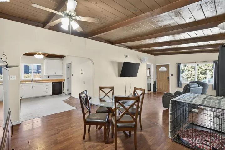 Dining area featuring arched walkways, ceiling fan, healthy amount of natural light, a wooden ceiling with exposed beams, and dark wood-style flooring