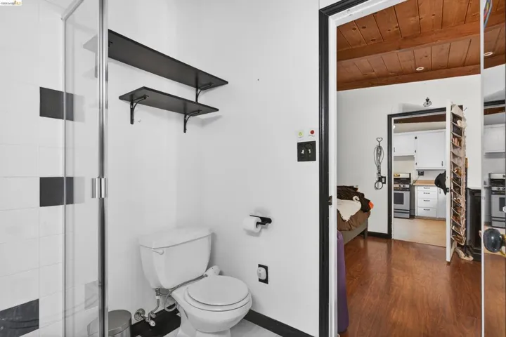 Full bath with a stall shower, a wooden ceiling with exposed beams, and dark wood-style flooring
