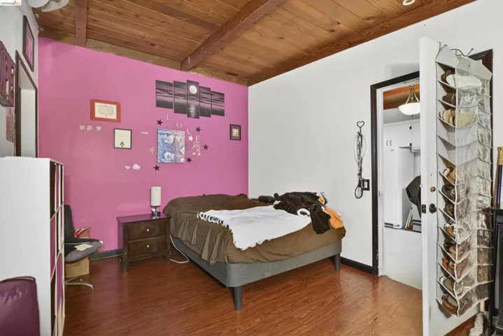 Bedroom with dark wood-type flooring and a wood ceiling with exposed beams