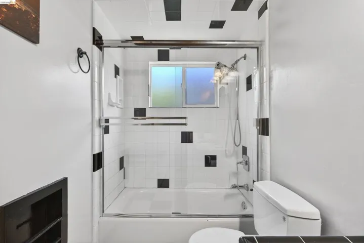 Bathroom featuring toilet and shower / bath combination with glass door