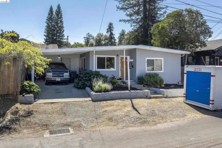View of front of property featuring an attached carport, driveway, and stucco siding