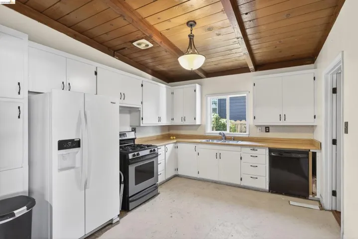 Kitchen featuring white refrigerator with ice dispenser, dishwasher, stainless steel gas range, hanging light fixtures, and light countertops