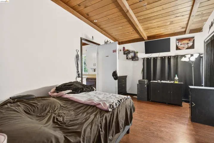 Bedroom with dark wood finished floors and a wood ceiling with exposed beams