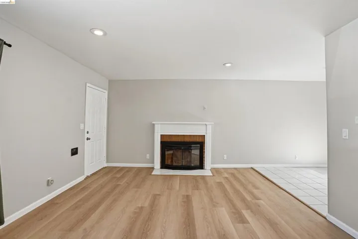 Unfurnished living room with light wood-type flooring, a fireplace with flush hearth, and recessed lighting