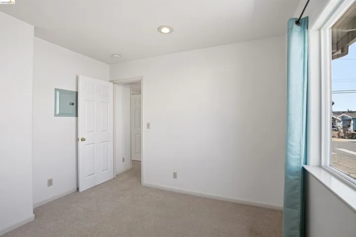 Spare room featuring electric panel, light colored carpet, and recessed lighting