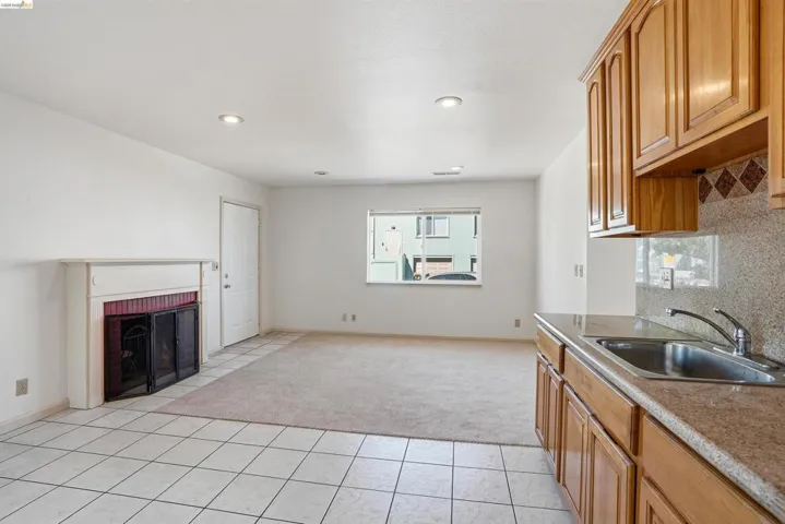 Kitchen with backsplash, wood finish cabinets, a brick fireplace, light tile patterned floors, and recessed lighting