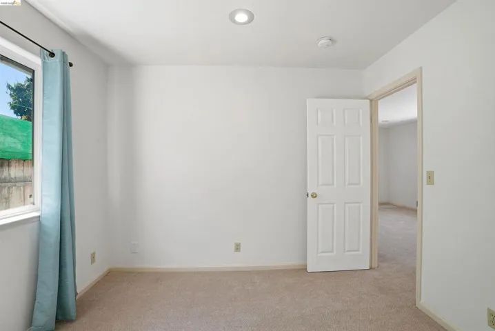 Empty room with light colored carpet and baseboards