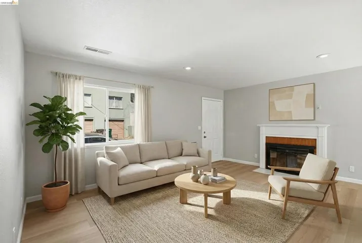 Living area featuring light wood finished floors, a fireplace with flush hearth, and recessed lighting