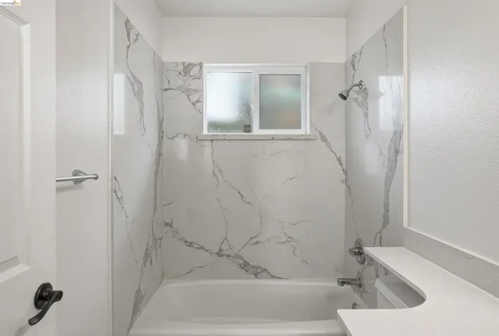 Bathroom with vanity and a combined bath / shower with marble appearance