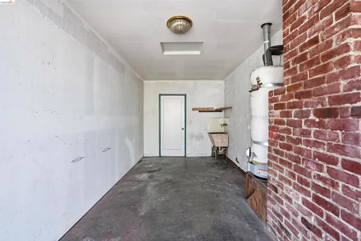 Hallway with concrete floors, brick wall, and water heater