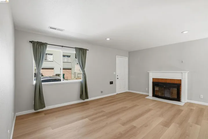 Unfurnished living room with light wood-style flooring, a brick fireplace, and recessed lighting