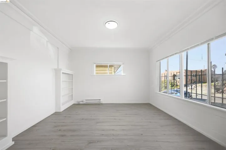 Empty room with light wood-style floors, crown molding, and a baseboard heating unit