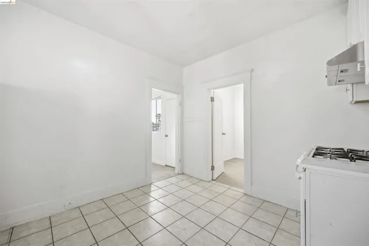 Kitchen featuring white gas range, range hood, white cabinets, and light tile patterned flooring