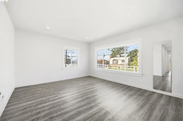 Empty room with dark wood-type flooring, healthy amount of natural light, and recessed lighting