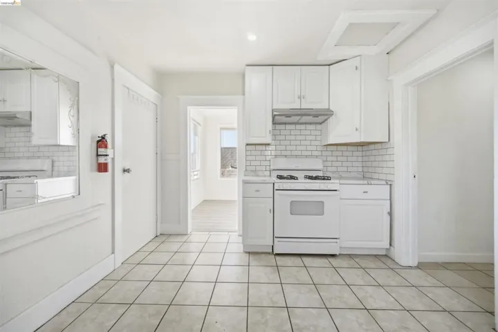 Kitchen featuring white cabinets, white range with gas cooktop, light countertops, recessed lighting, and light tile patterned floors