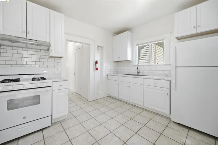 Kitchen with white appliances, white cabinetry, and light tile patterned floors