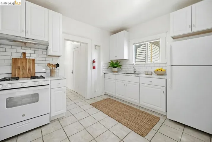 Kitchen featuring white appliances, white cabinetry, and light tile patterned floors