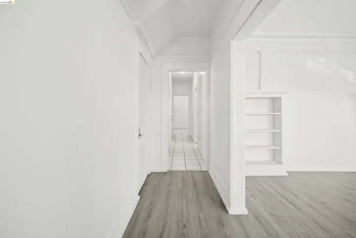 Hallway featuring light wood-type flooring, vaulted ceiling, and built in shelves