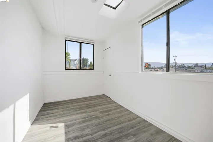 Empty room with dark wood-type flooring and baseboards