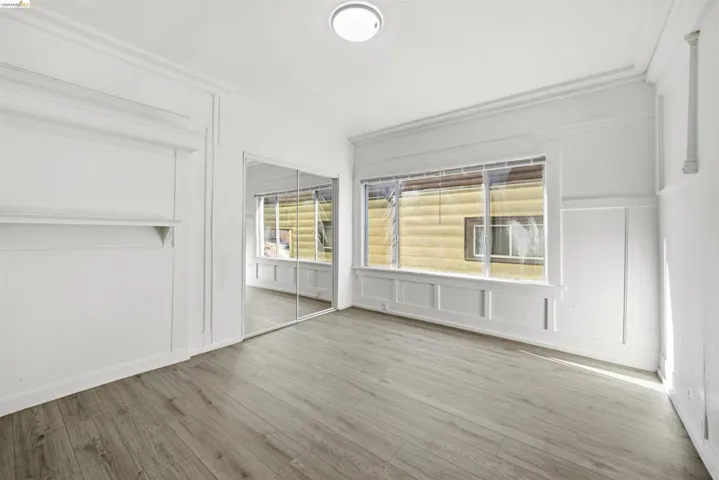 Unfurnished bedroom featuring a closet, a decorative wall, multiple windows, and light wood-style flooring