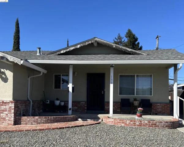 View of front of home with a porch, roof with shingles, and stucco siding