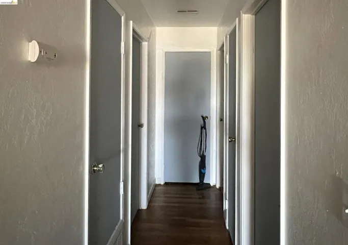 Corridor with a textured wall and dark wood-style floors
