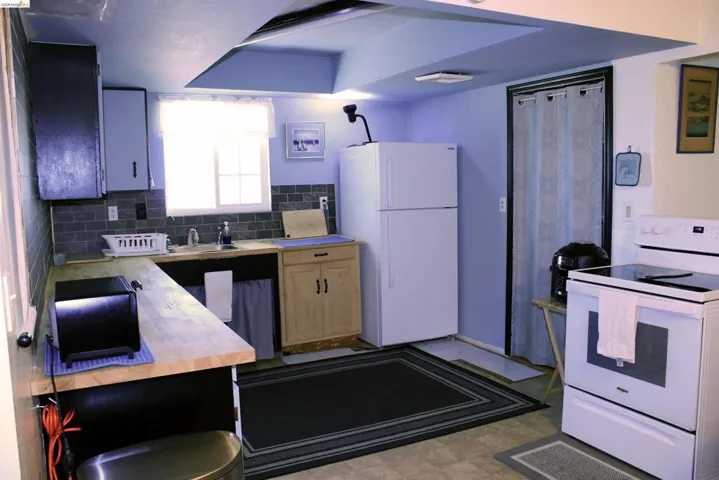 Kitchen featuring white appliances, tasteful backsplash, butcher block counters, and light flooring