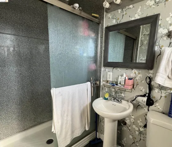 Full bath with a stall shower and wallpapered walls