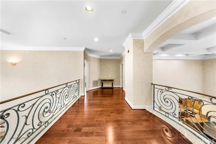 An upstairs bridge hallway connects the primary suite on one side to two junior ensuite bedrooms on the opposite side.