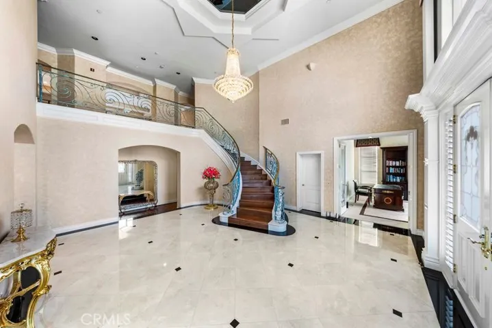 A grand foyer showcases a graceful, handcrafted Roman-style staircase railing complemented by soaring ceilings.