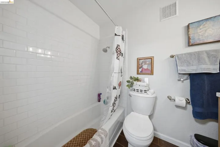 Full bathroom featuring shower / tub combo with curtain and a textured wall
